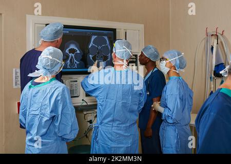 Discutere le loro opzioni. Shot di un team di chirurghi che discutono di un paziente esami medici durante l'intervento chirurgico. Foto Stock