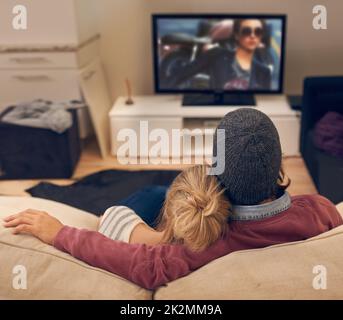 Tutto è divertente quando sono stati insieme. Vista posteriore di una giovane coppia che guarda la TV insieme. Foto Stock