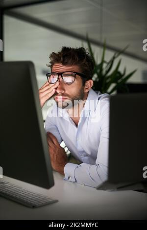 Mettendo nelle ore per realizzare il successo. Shot di un giovane uomo d'affari che lavora tardi in ufficio. Foto Stock