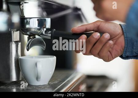 Il cuore del buon caffè si trova nella sua preperazione. Shot ritagliato di un barista che prepara una tazza di caffè. Foto Stock