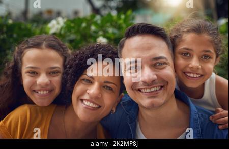 Il tempo della famiglia rende ogni faccia un volto felice. Ritratto corto di una famiglia felice che passa un po 'di tempo insieme al parco. Foto Stock