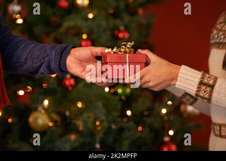 E' una tradizione della vigilia di Natale. Scatto corto di una coppia che si scambiano un regalo di natale. Foto Stock