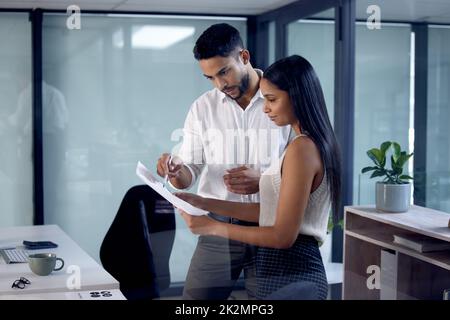 Che ne pensi. Immagine di due colleghi di lavoro che leggono insieme alcuni documenti. Foto Stock