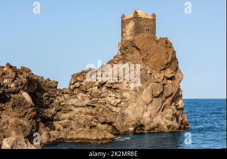 Una torre di guardia medievale arroccata su un affioramento di lava vulcanica che domina il Mar Ionio, vicino al piccolo villaggio di Santa Tecla, Acireale, Sicilia Foto Stock