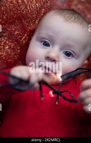 Adorabile bambino di Natale che gioca con le luci di festa Foto Stock