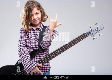 Ragazza sorridente che suona la chitarra dando un segno corna Foto Stock