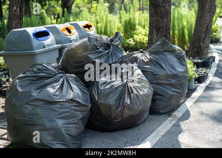 Cestino di plastica sacchetti di rifiuti sul marciapiede in parco, concetto di ambiente pulito. Foto Stock