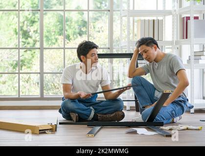 Servizio di ristrutturazione della casa. Due falegnami hanno discusso il tipo di banco che è assemblato. Atmosfera di lavoro mattutina nel soggiorno. Handyman che installa il banco di legno nella nuova casa. Foto Stock