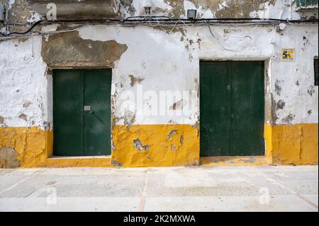 Vecchie porte in legno dipinte di verde su un edificio bianco con un bordo giallo in Spagna Foto Stock