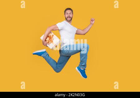 Corriere regalo a mezz'aria. Un ragazzo energico che corre veloce con la confezione regalo. Consegna di regali e regali Foto Stock