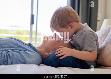 Espressioni di amore. Scatto corto di un ragazzo baciante sua madre a casa. Foto Stock