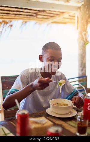 Provate la cucina locale. Shot di un giovane che mangia una ciotola di tagliatelle in un ristorante in Thailandia. Foto Stock