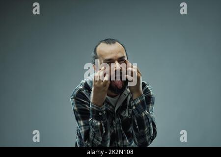 Imbecilic o uomo maniaco che tira un volto grottesco alla fotocamera Foto Stock