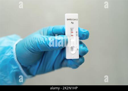 Il medico asiatico in tuta PPE mostra risultati positivi del test con saliva A. Foto Stock