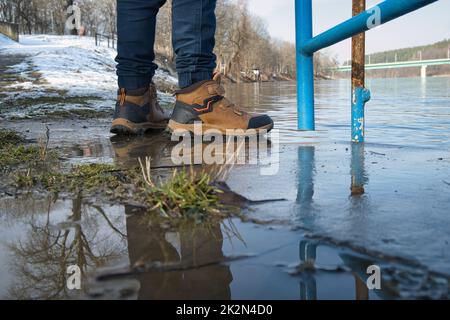 Persona che indossa stivali da trekking in piedi su pavimenti bagnati Foto Stock
