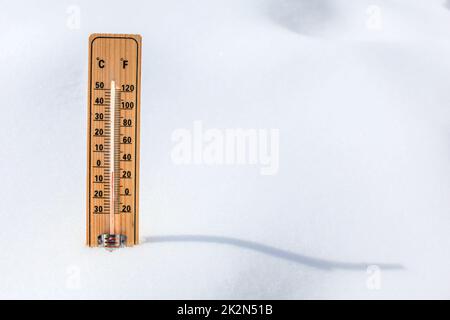 Termometro in legno in piedi nella neve, che mostrano una bassa temperatura, spazio per il testo a destra. L'inverno prossimo concetto. Foto Stock