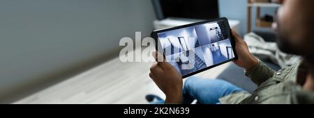 Imprenditore Guardando telecamera TVCC filmati sulla tavoletta digitale Foto Stock