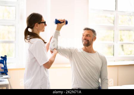 Riabilitazione fisica terapeuta aiutare l'uomo Foto Stock