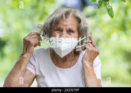 Donna anziana che indossa una maschera protettiva contro i virus Foto Stock
