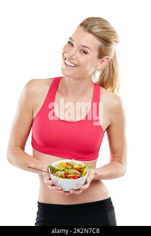 Mangiare meglio, sentirsi meglio. Studio di una giovane donna atletica che mangia una ciotola di insalata. Foto Stock