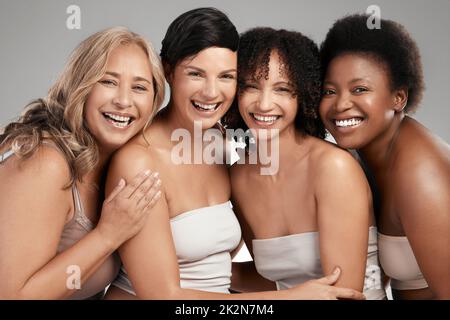 Beh, non condividere mai i nostri segreti di bellezza. Girato di un gruppo diversificato di donne in piedi e abbracciarsi l'un l'altro in studio. Foto Stock