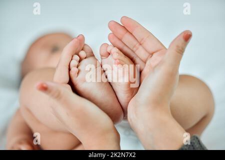 I piedi più piccoli lasciano le impronte più grandi sul vostro cuore. Closeup shot di una donna che tiene le sue bambine piedi piccoli. Foto Stock