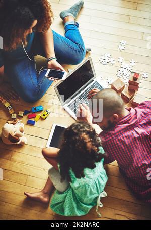 Trovare cose divertenti da fare online. Un'immagine di una famiglia di tre persone che utilizza la tecnologia moderna a casa. Foto Stock