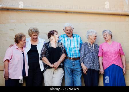 Più ci piace, più ci piace la vita. Colpo di un gruppo di anziani in piedi contro una parete esterna. Foto Stock