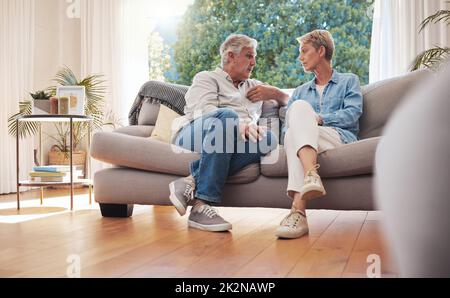 Coppia anziana, colloquio serio e comunicazione circa i problemi e le edizioni di Unione mentre sedendosi sul divano nel paese. Uomo e donna maturi che parlano e. Foto Stock