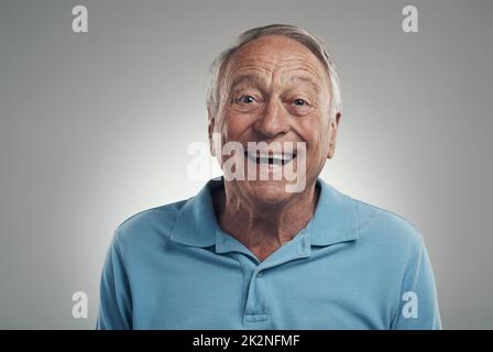 È il momento di sorridere per un po'. Scatto di un uomo che sorride felicemente alla fotocamera in uno studio su sfondo grigio. Foto Stock