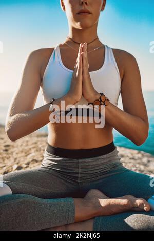 Essere tranquilli è uno stile di vita. Shot di una giovane atletica che pratica yoga sulla spiaggia. Foto Stock