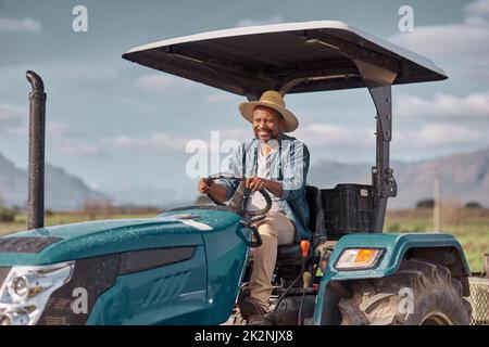 Fuori ai campi andiamo. Colpo di un uomo maturo che guida un trattore in un'azienda agricola. Foto Stock