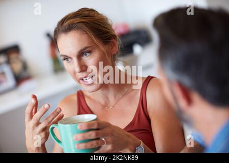 Ma thats esattamente che cosa im dicendo. Scatto corto di una giovane donna attraente che ha una conversazione seria con il suo marito mentre tiene una tazza di caffè. Foto Stock