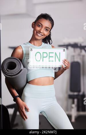 Ti aiuta a far risplendere il tuo bagliore. Ritratto di una giovane donna che tiene un segno aperto nella sua palestra. Foto Stock