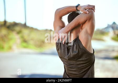 Allunga bene in modo da poter correre i tuoi limiti. Scatto retrospettivo di un giovane sportivo che allunga le braccia mentre si esercita all'aperto. Foto Stock