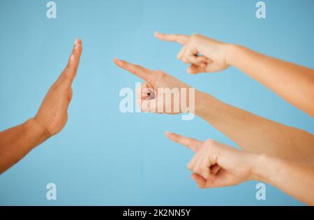 Questo deve essere messo in attesa. Immagine di un gruppo di persone irriconoscibile che indica la mano tenuta in un gesto di arresto su uno sfondo blu. Foto Stock