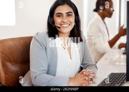 Garantisce un servizio rapido ed efficiente. Ritratto di un giovane agente del call center che lavora in ufficio con la sua collega sullo sfondo. Foto Stock