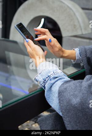 La ragazza si siede in un bar e tiene un telefono touch, un robot e la comunicazione via Internet. Robot online, accesso remoto. Foto Stock