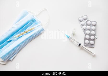 Preparazione per la vaccinazione contro il covid-19. Siringa, vaccino, pillole, maschera medica. Foto Stock