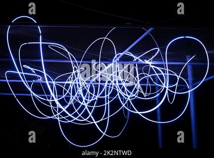 Il flusso di elettroni come fasci di luce spaghetti è illuminato di bianco. Un fascio luminoso di luci a LED bianche mostra un flusso di particelle elettriche o fotoni luminosi Foto Stock