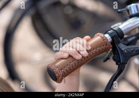 Primo piano di una mano di un bambino che tiene il manubrio di una bicicletta Foto Stock