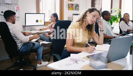 Oggi non va a modo mio. Scatto di una giovane donna d'affari che guarda stressata mentre usa un laptop in un ufficio moderno. Foto Stock