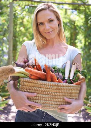 Celebrare un raccolto abbondante. Una donna che tiene un cesto di verdure fresche. Foto Stock