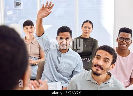 Se volete saperne di più, dovete fare altre domande. Scatto di un giovane uomo d'affari che alza la mano durante una presentazione in un ufficio. Foto Stock