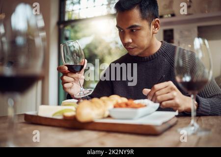 USA tutti i tuoi sensi. Shot di un uomo gustando un piatto di formaggi e degustando vini diversi. Foto Stock