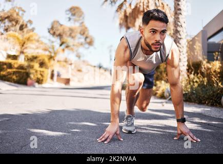 Im già pronto per vincere maratone. Scatto a tutta lunghezza di un bel giovane uomo accoccolato in una posizione impostata prima di correre all'esterno. Foto Stock