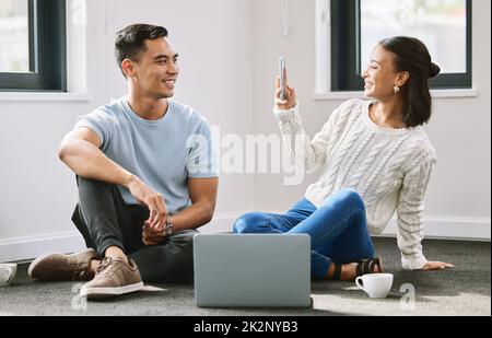 Voglio ricordare questo giorno per sempre. Scatto a tutta lunghezza di una giovane donna attraente seduta e che porta fotografi del suo ragazzo nella loro nuova casa. Foto Stock