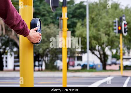 In attesa di camminare. Colpo di mano di uomo premendo il pulsante di incrocio ad un incrocio. Foto Stock