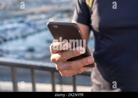 Primo piano di una mano maschile che tiene uno smartphone all'aperto Foto Stock
