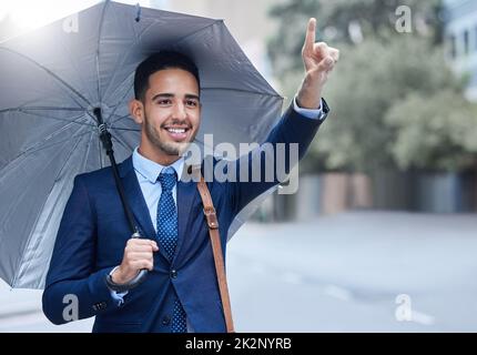 Taxi. Scatto corto di un bel giovane uomo d'affari con un ombrello che si accoccolava un taxi mentre la mattina si spostava al lavoro. Foto Stock